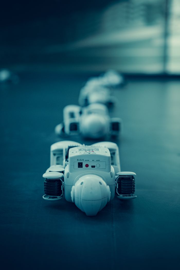 why-choose-us Vertical shot of white robots aligned on a dark surface, emphasizing technology.