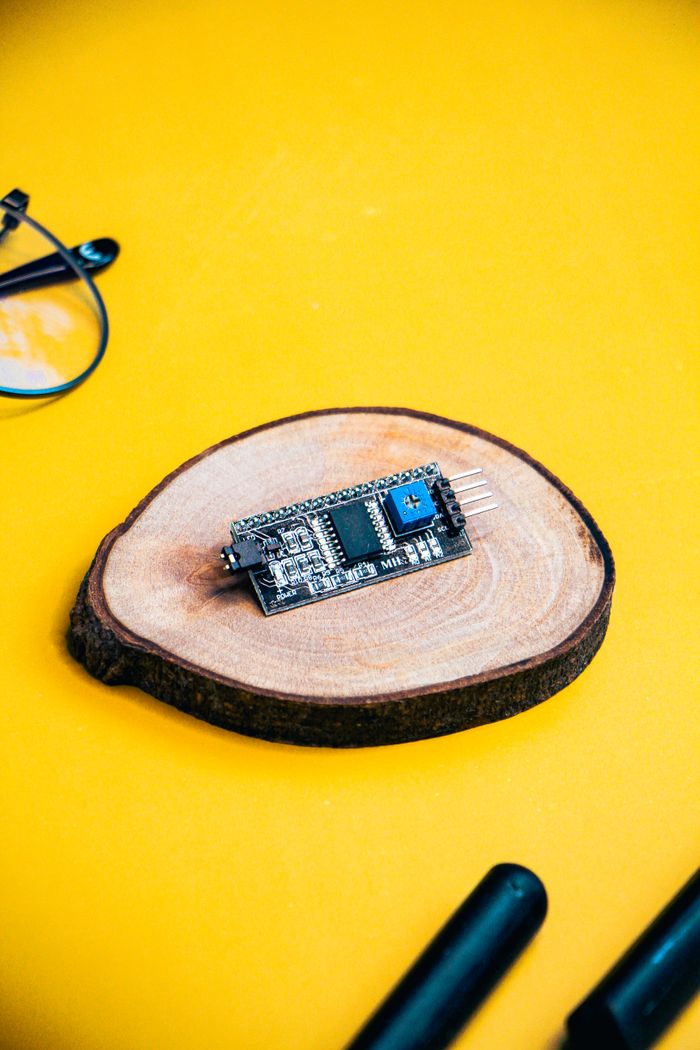 gallery-1 Microcontroller on a wooden slice with a vibrant yellow background, ideal for tech and electronics themes.